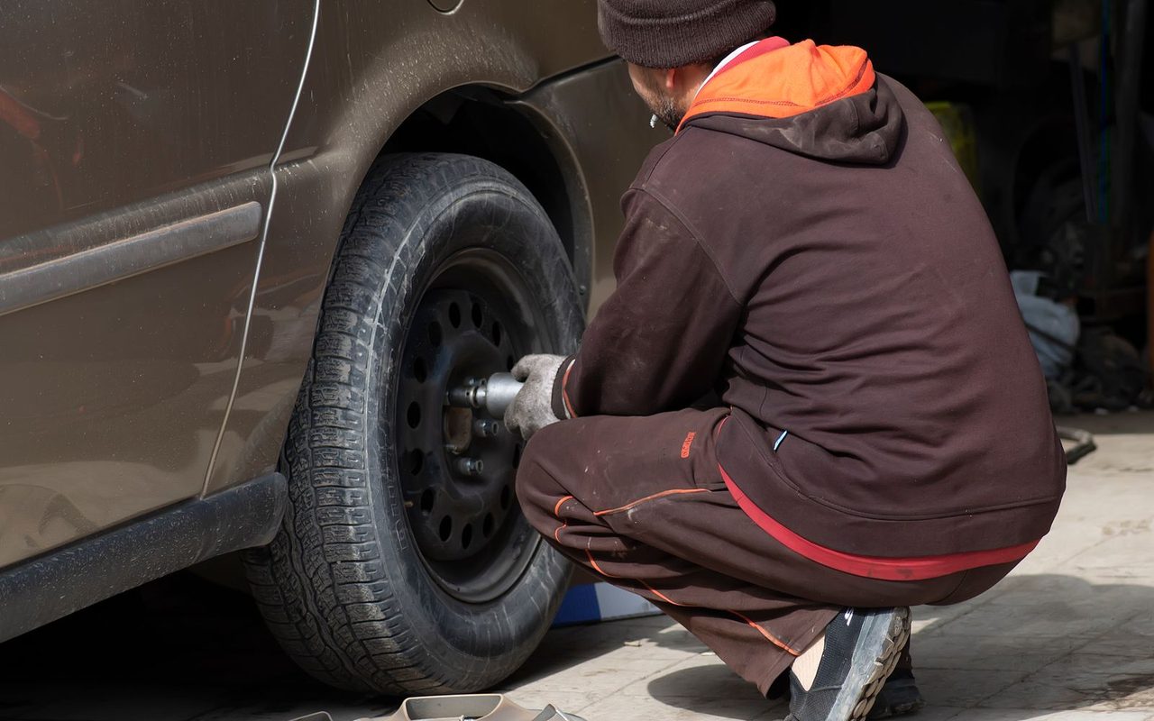A mechanic changing a single tire on a car in an auto repair shop